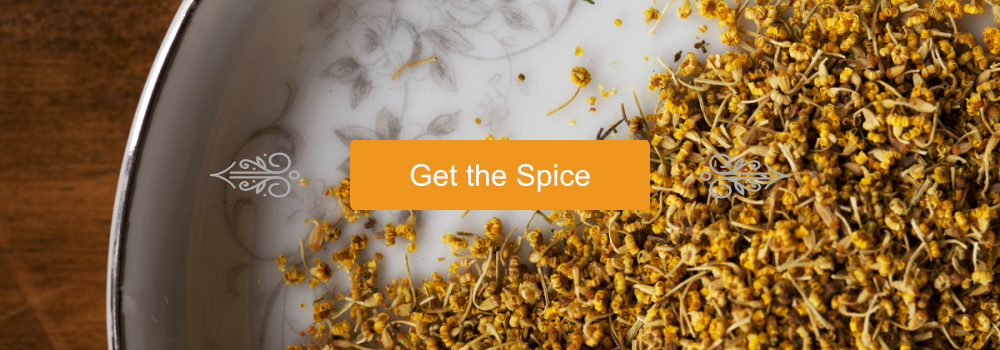 "Get the Spice" button with scroll embellishments upon a Fennel Pollen background